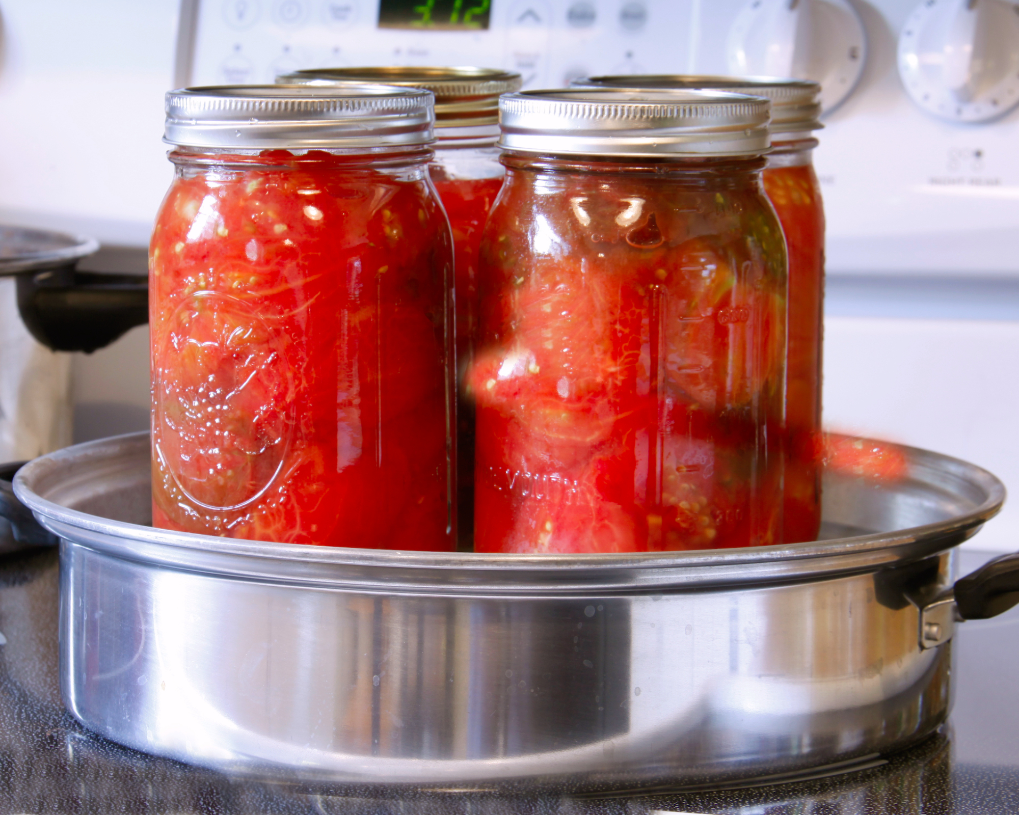 canning tomatoes in jars on a stovetop