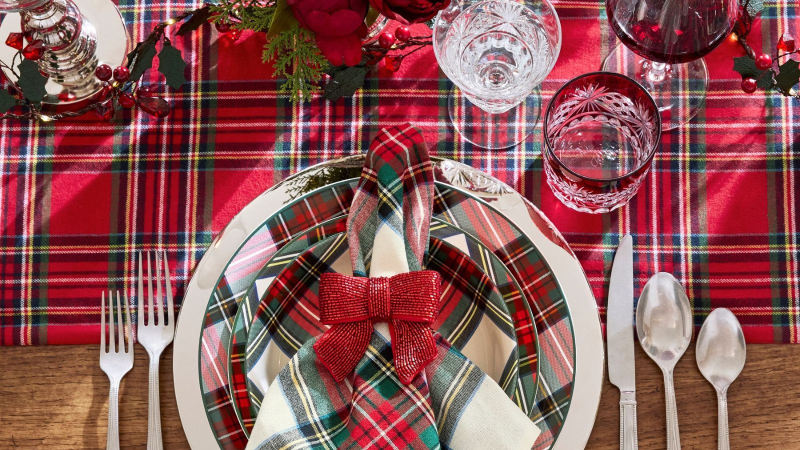 Red plaid table runner with white plaid plates, silver flatware, and red glitter bow napkin rings
