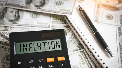 inflation written on calculator screen with pen and notepad and hundred dollar bills