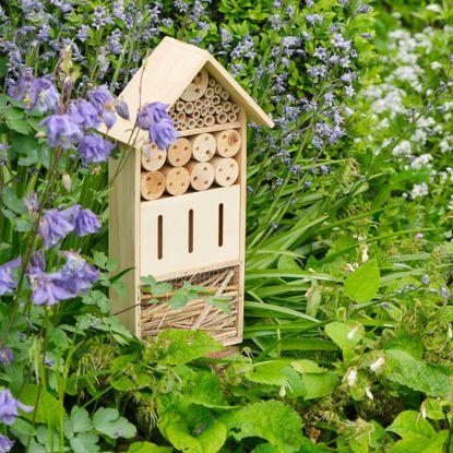 An insect hotel or bee hotel in a summer garden. An insect hotel is a manmade structure created to provide shelter for insects in a variety of shapes and sizes and materials.