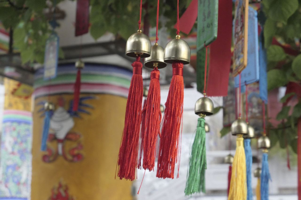Buddhist colorful Prayer cards and bells attached to a tree in a temple courtyard