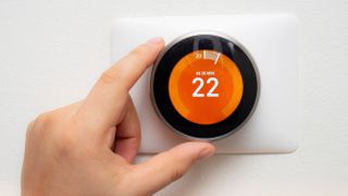 The control panel of a smart thermostat being adjusted by hand