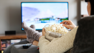 Best TVs under £1000: Image depicts person with popcorn in front of TV