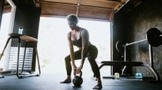 A woman working out in garage gym doing kettlebell squats