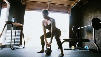 A woman working out in garage gym doing kettlebell squats