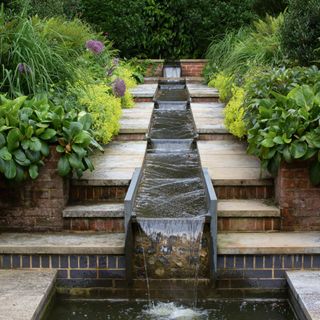 garden with water feature cascading along steps with planting either side