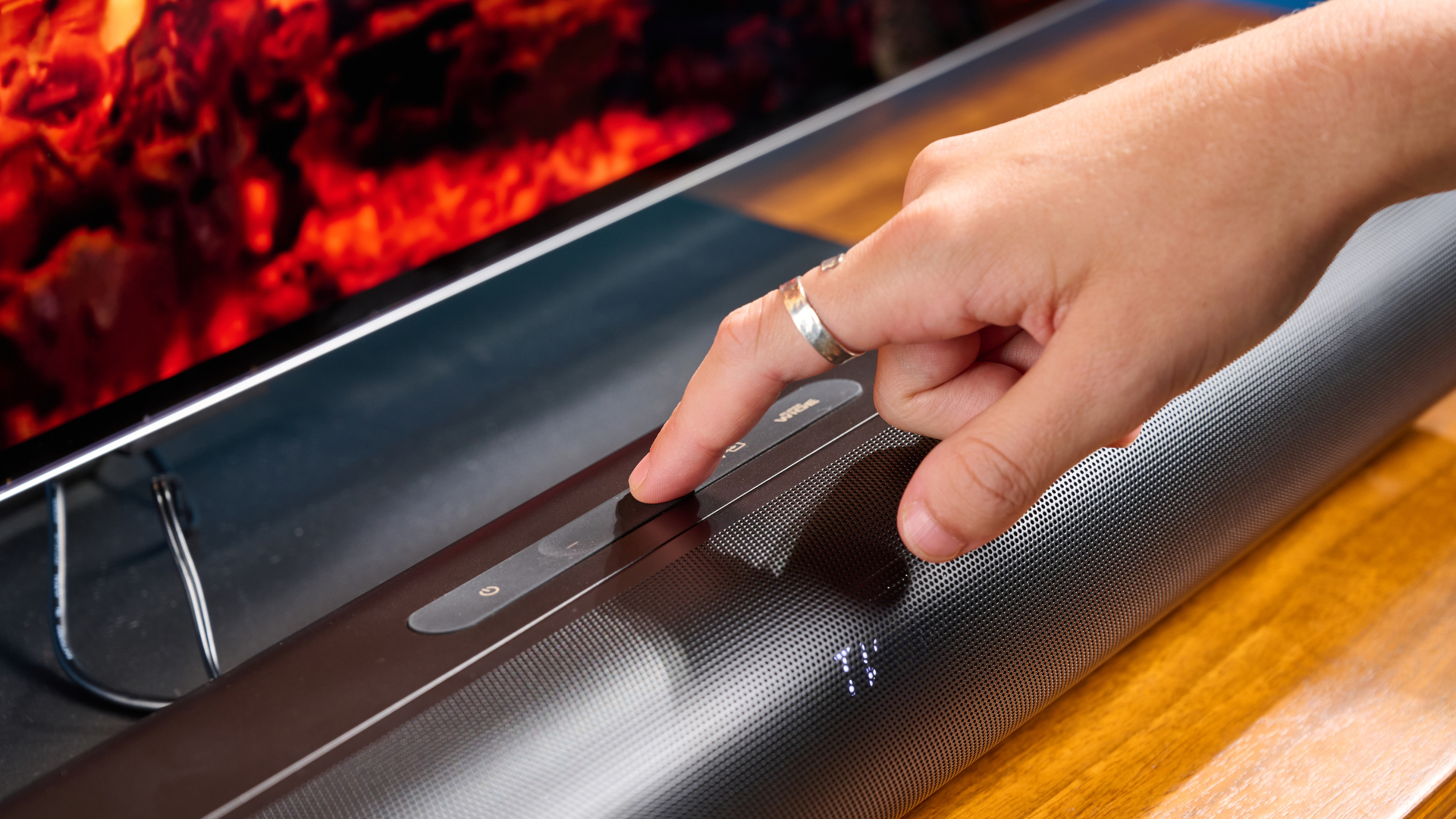 the creative stage pro soundbar and subwoofer, a super-budget home cinema system with 2.1 channels and a remote control photographed on a wooden tv stand with a TV behind
