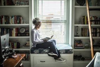 A woman reads a book in a sunny room.