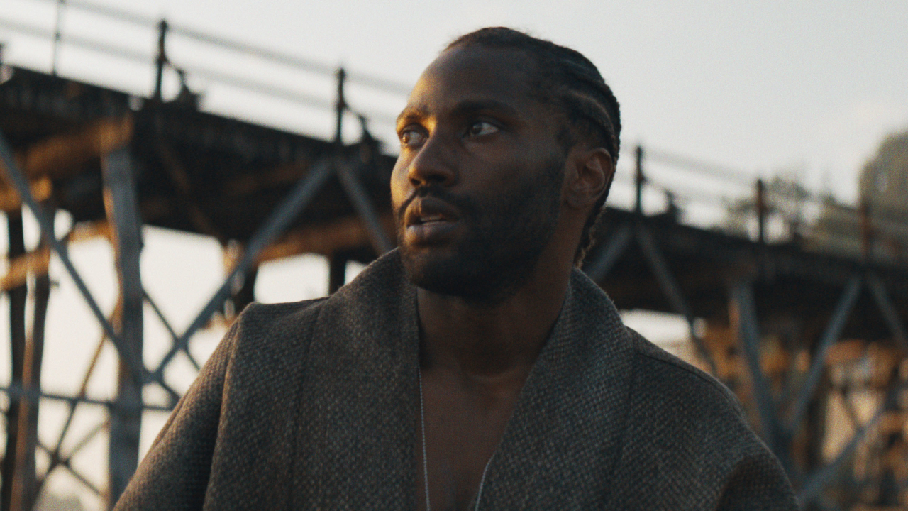 John David Washington looks cryptically off to the distance in The Creator.