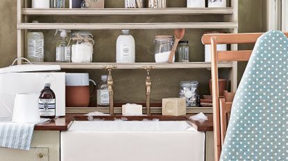 An example of utility room shelving ideas showing simple wooden shelves sat behind a faucet