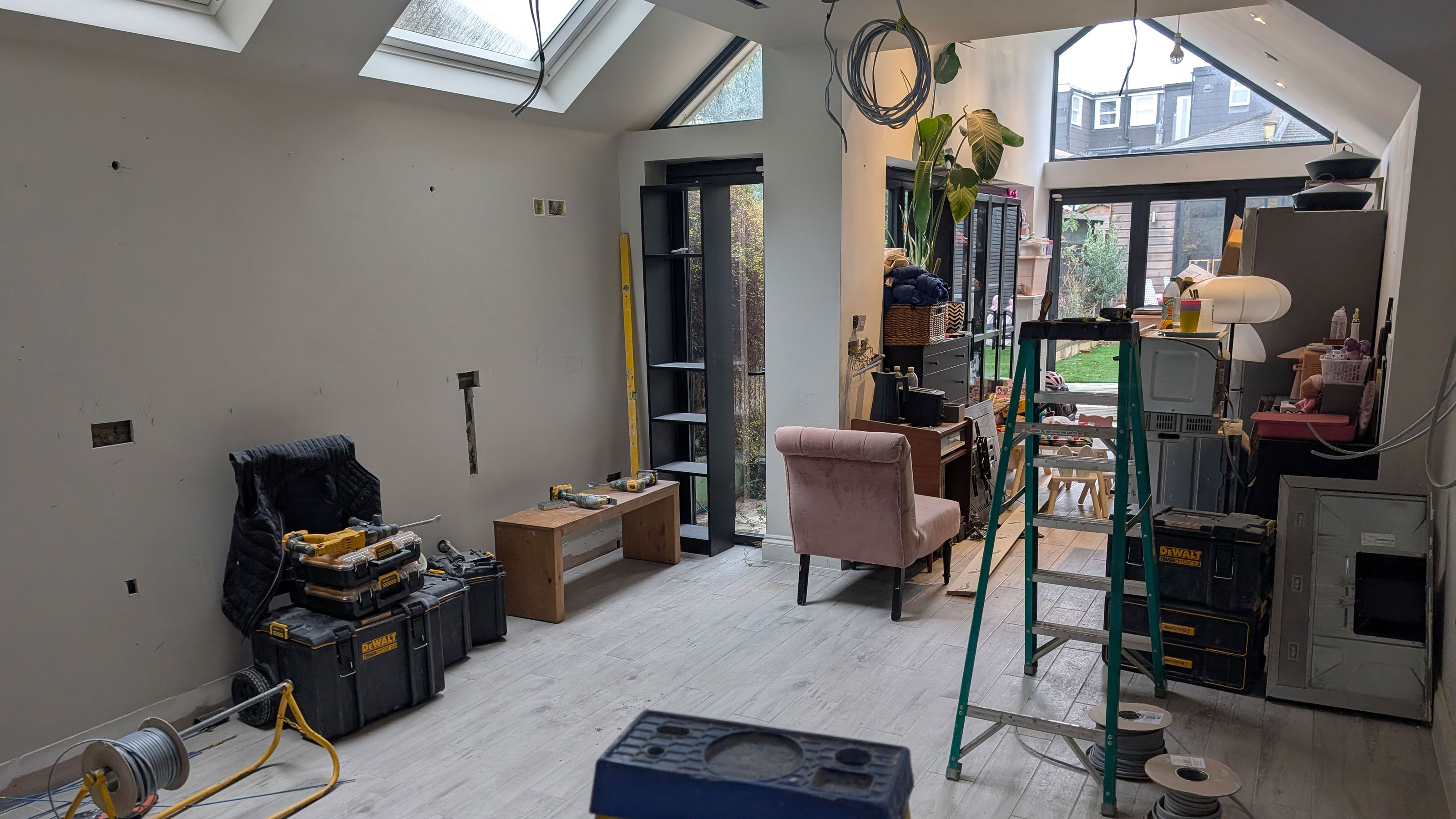 Kitchen extension with exposed wiring, furniture scattered around and no appliances in place