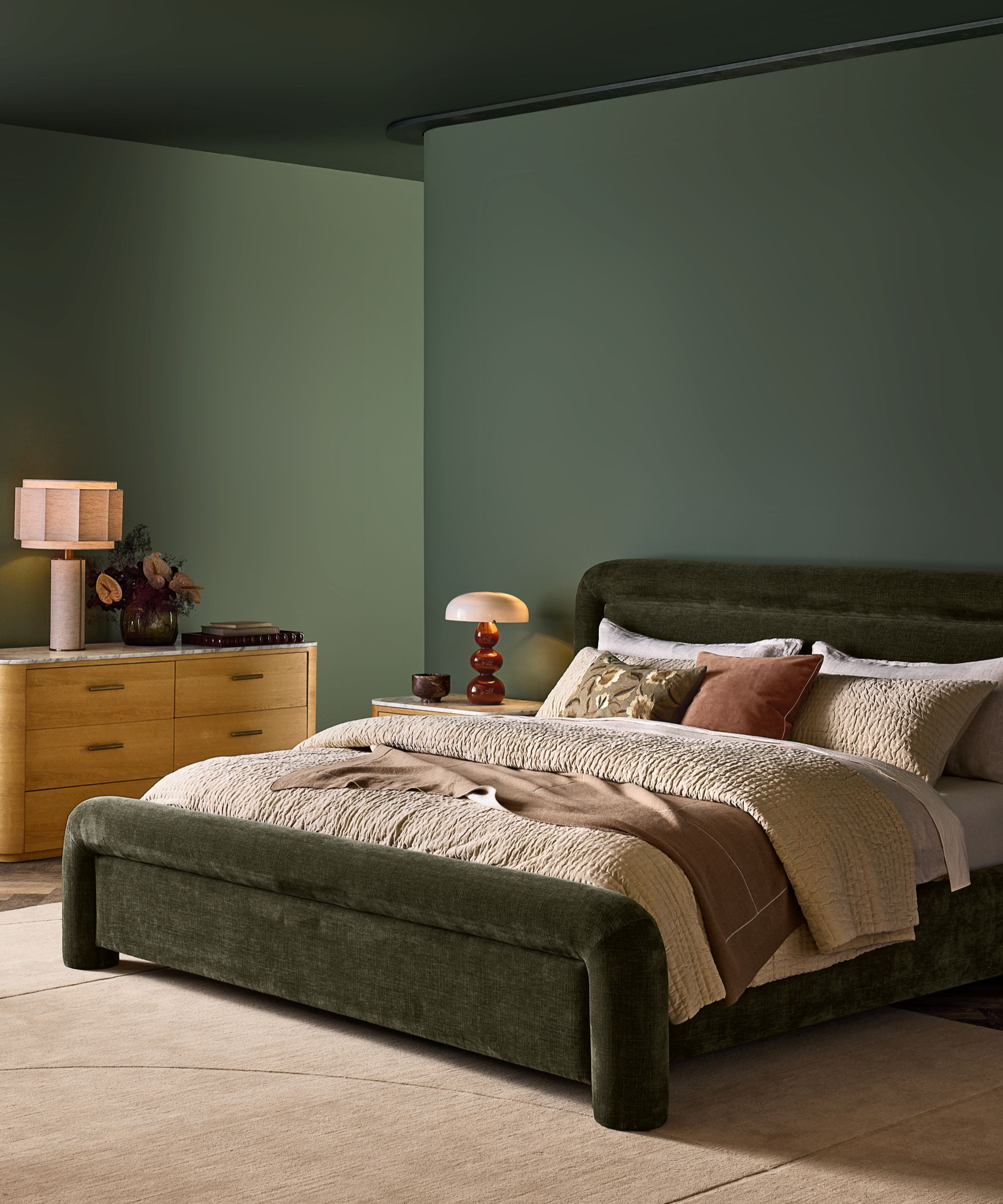 a green bedroom with a green bedframe, tan bedding, and accent pillows