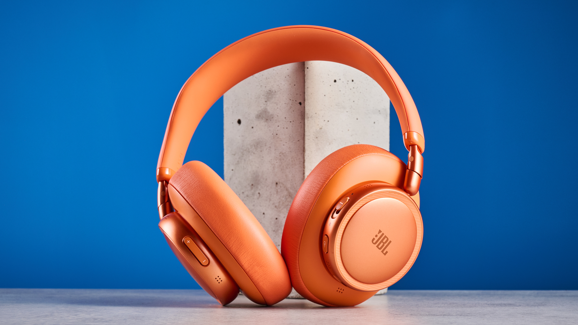 the jbl live 780NC in orange photographed against the blue tom's guide background