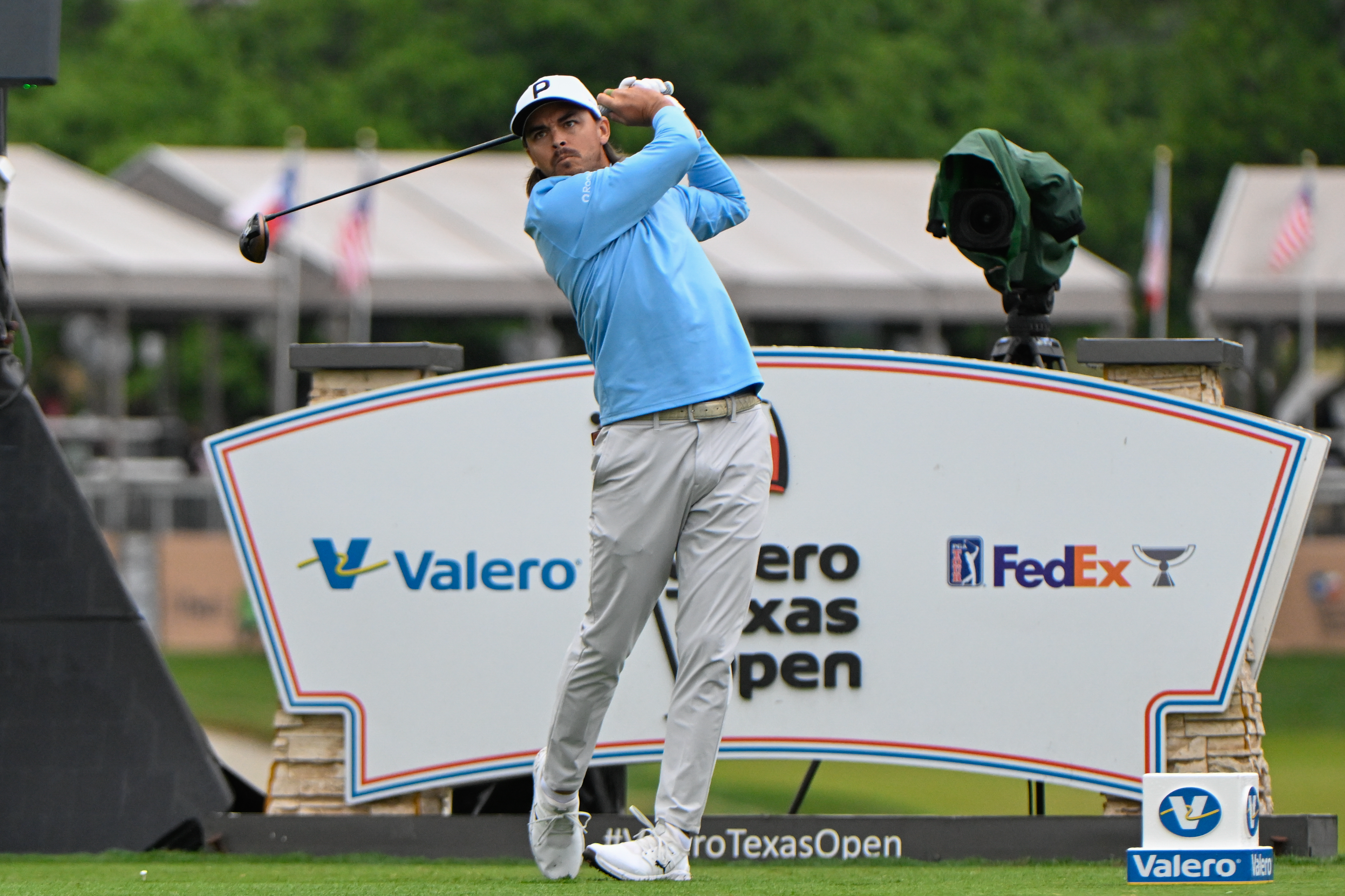 Rickie Fowler hits a tee shot in front of the Valero Texas Open board