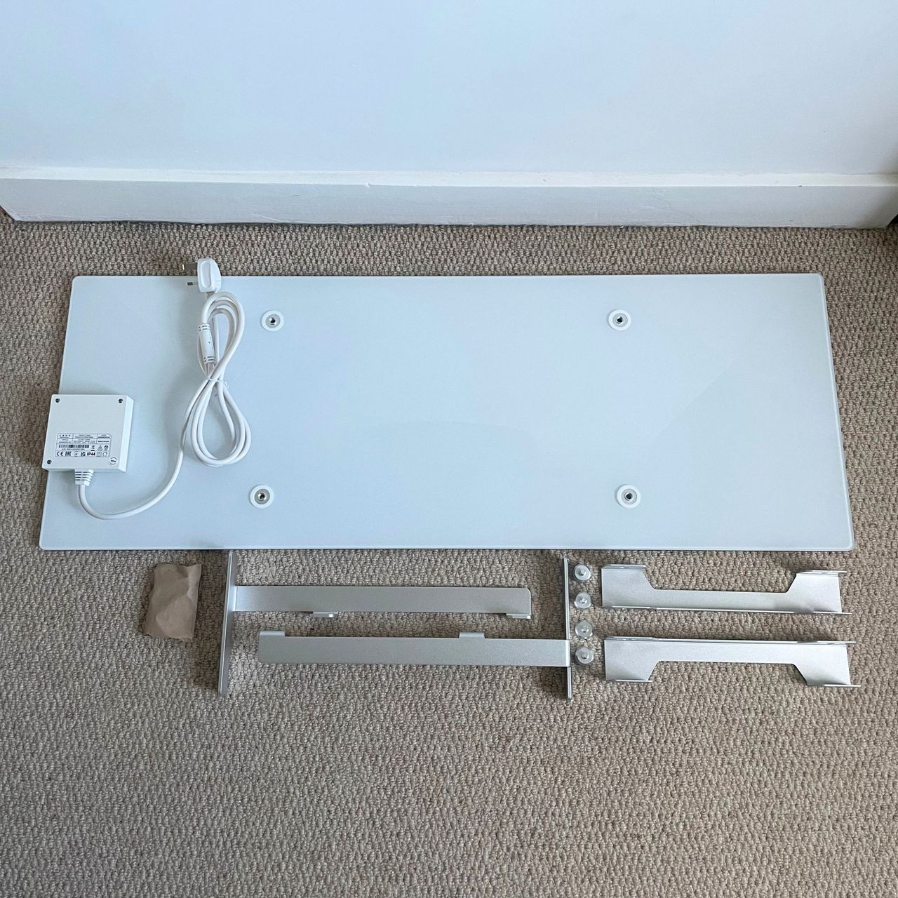 The components of the Aeno Premium Eco Smart Heater laying on cream carpet
