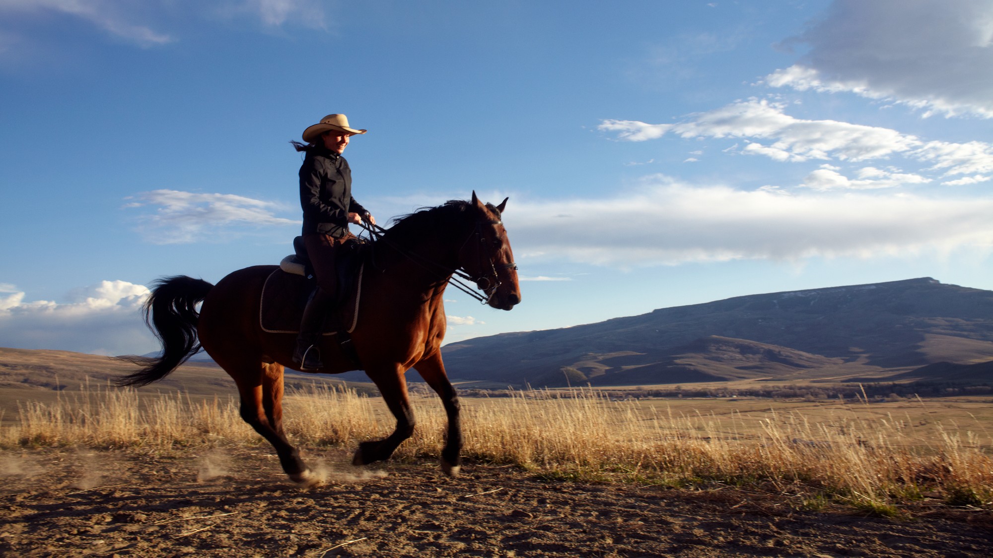 A woman rides a horse across a field in Colorado