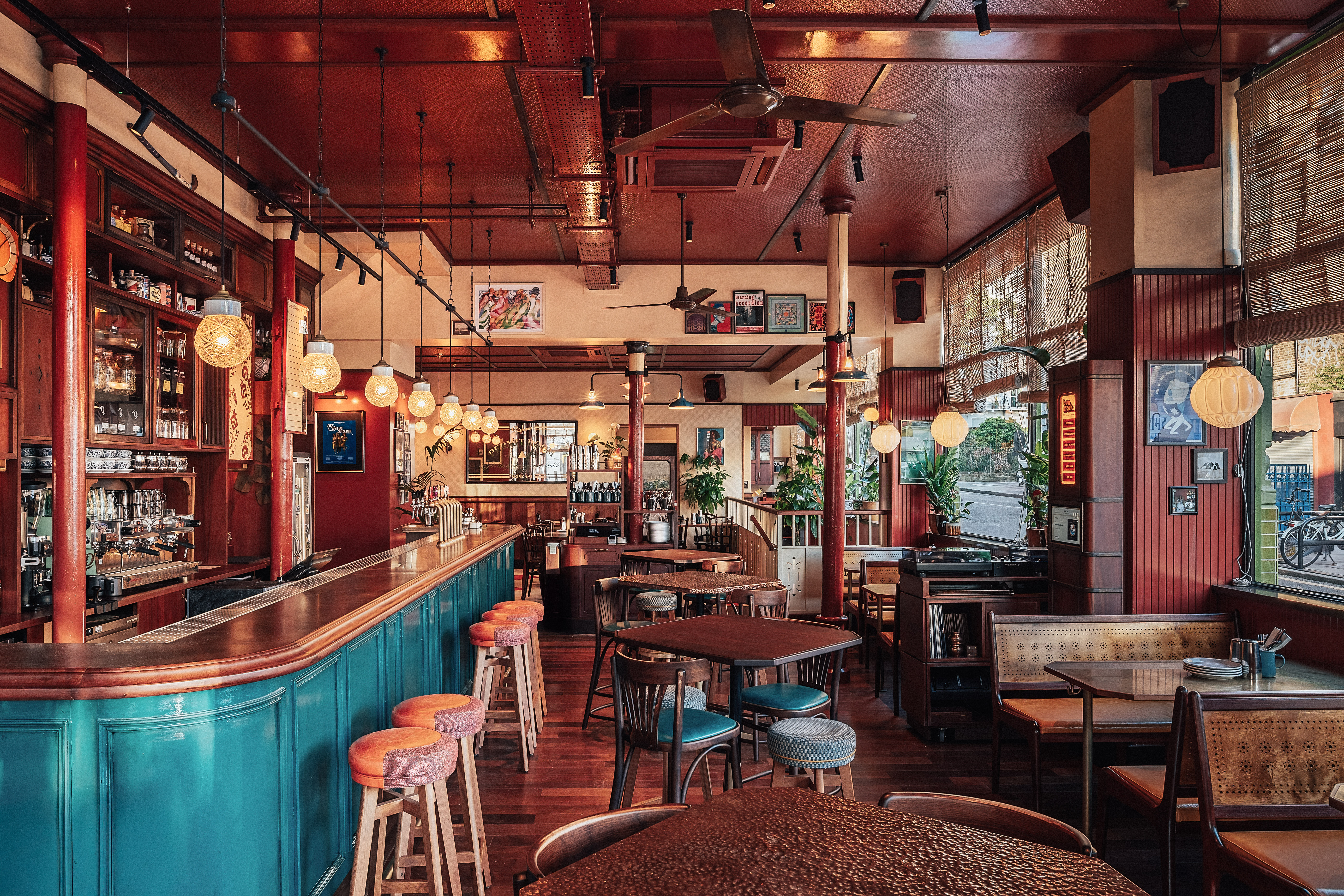 An old English pub has been repurposed into a layered, nostalgic Indian cafe punctuated by wooden surfaces in brown and tile blue, leather accents, and warm lighting.