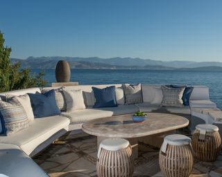 An outdoor seating area at a Corfu villa with sea views, blue cushions and large stone table