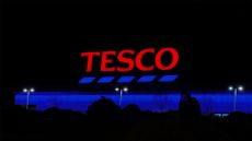 Tesco supermarket logo and branding pictured on a sign illuminated at night at a shopping mall in Budapest, Hungary.