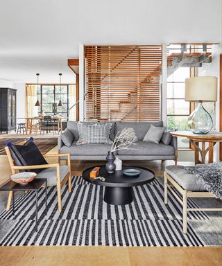 A living room with grey sofa, wooden furniture and black and grey striped rug