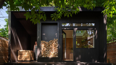 black wooden garden room in a tree filled garden with a oak clad working space, a sauna and a cold plunge