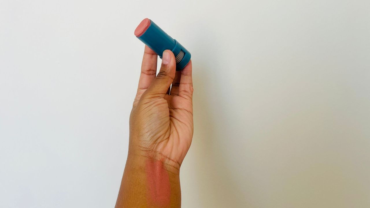 A person holding an opened Colorescience SPF lip balm.