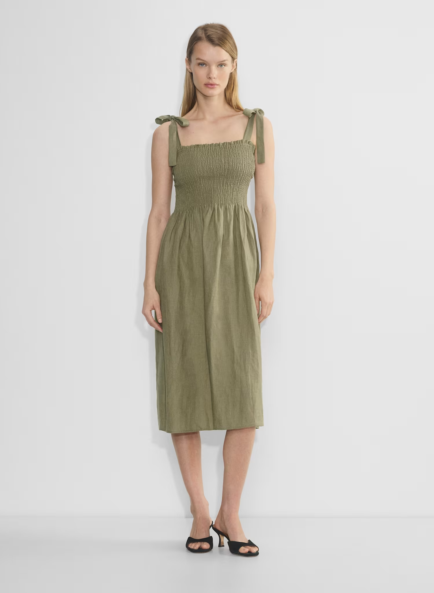 A model wearing a green smocked dress with shoulder bows