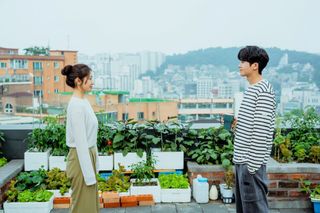 a woman and a man smile at each other on a seoul rooftop