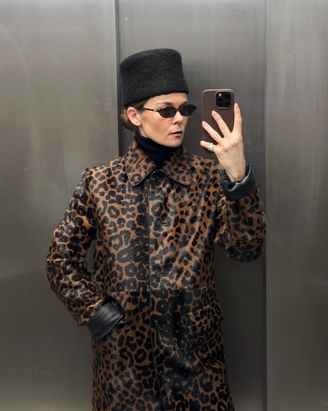 A woman in a pillbox hat and leopard coat.