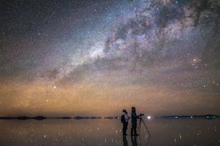 Two skywatchers take photos under the Milky Way at the Salar de Uyuni salts flats in Bolivia.