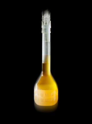 Oumere skincare serum in yellow test tube-like bottle against black background