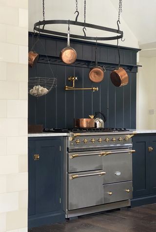devol kitchen with chrome lacanche range cooker and navy paneled backsplash and cabinetry