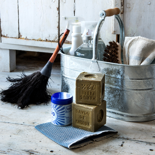 Metal cleaning caddy filled with cleaning products, and a feather duster sitting next to it