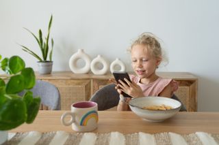 A young girl on her phone while eating