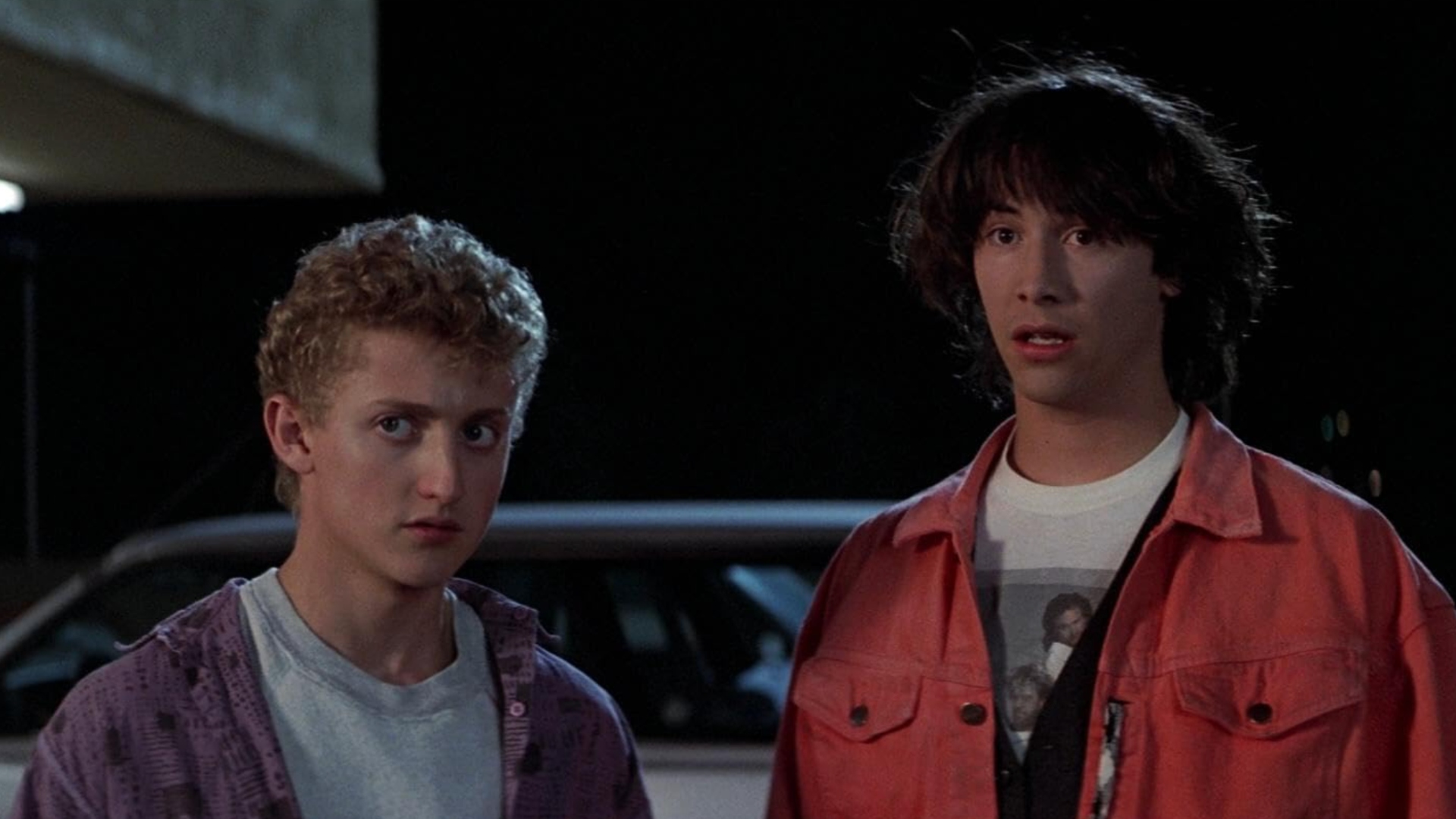 Screenshot from the movie Bill and Ted's Excellent Adventure. Bill (left) and Ted (right) are standing together looking bewildered.