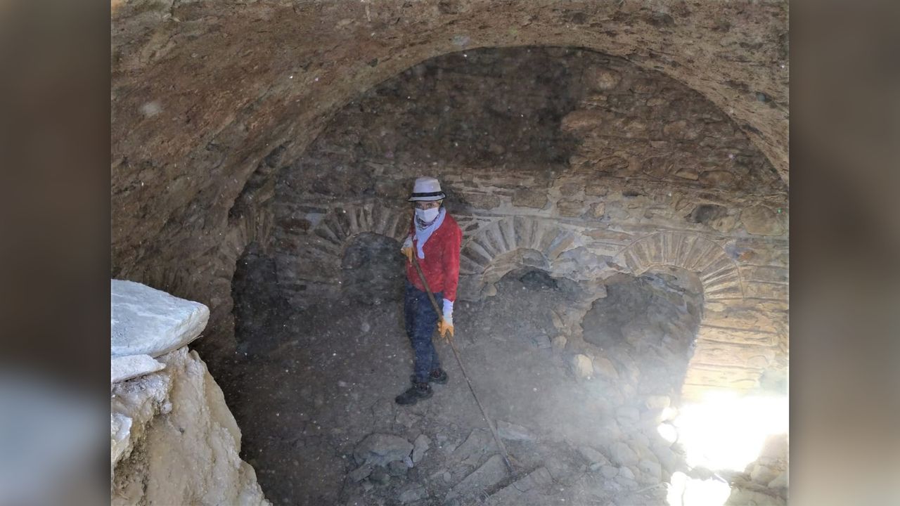 A researcher clears rubble from the site.