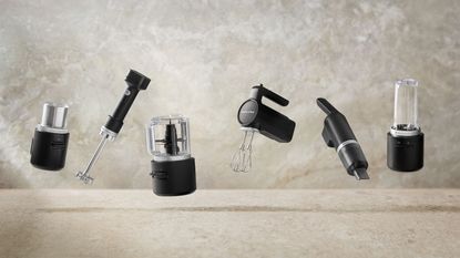 KitchenAid Go Cordless range: the coffee grinder, immersion blender, food processor, hand mixer, vacuum, and personal blender on a beige-gray background