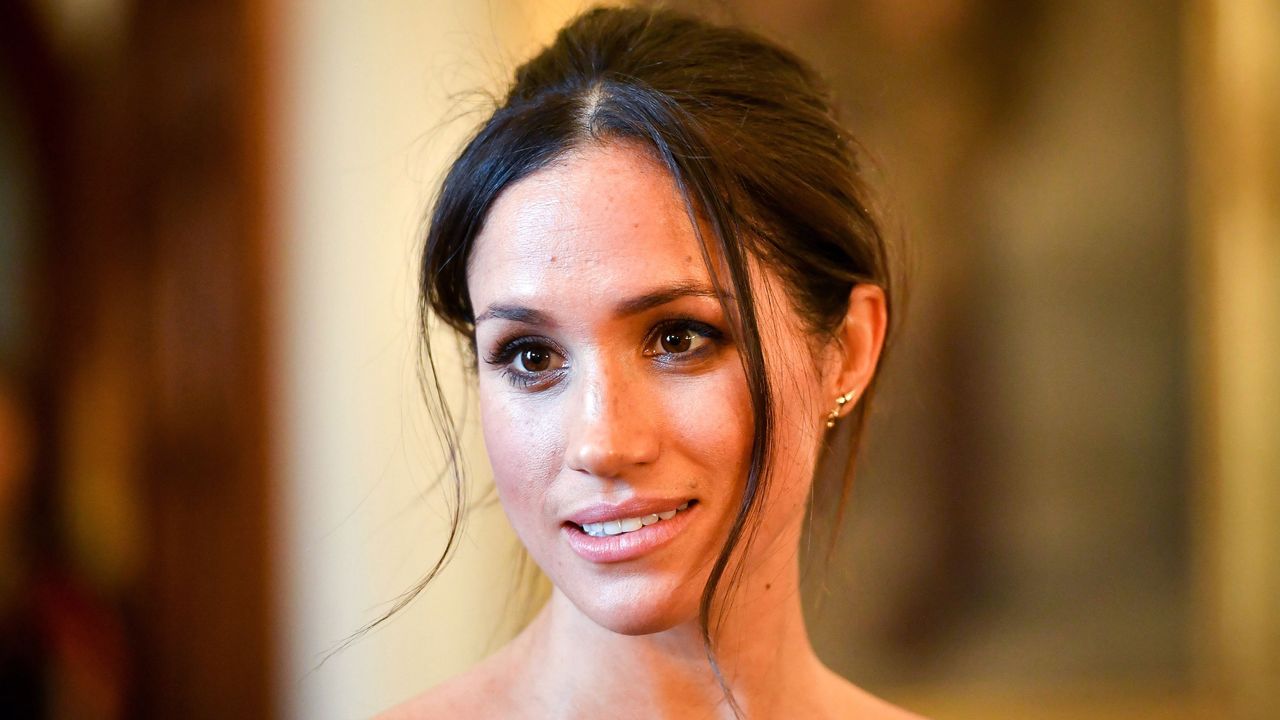 Meghan markle wearing an off the shoulder shirt and an updo