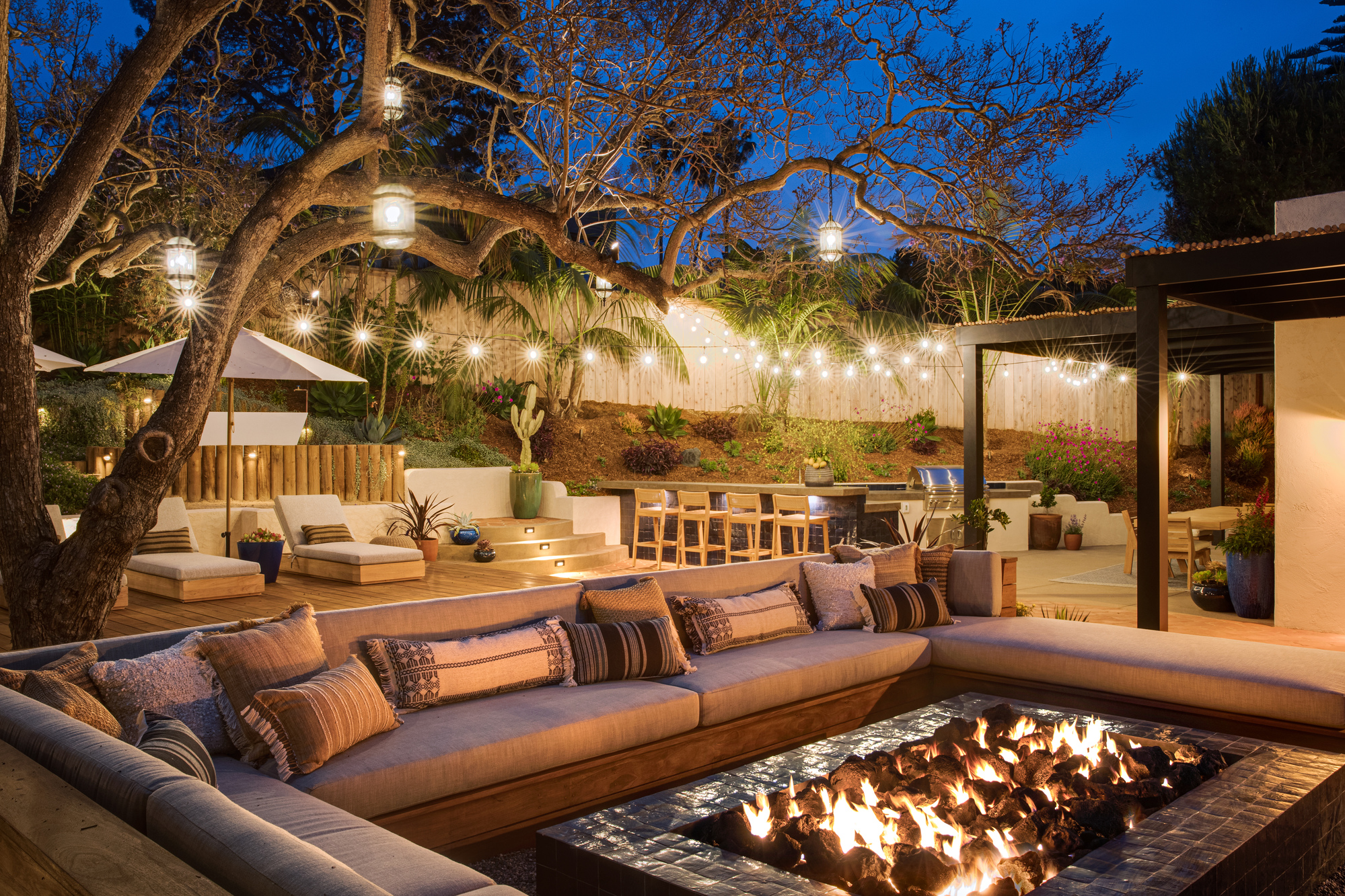 An outdoor space lit with a firepit, rattan lantens and string lights