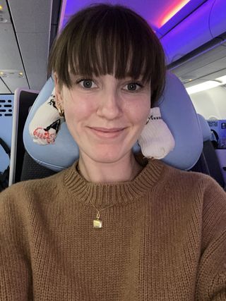 Halie LeSavage sitting on an airplane using two socks to curl her hair into two sections