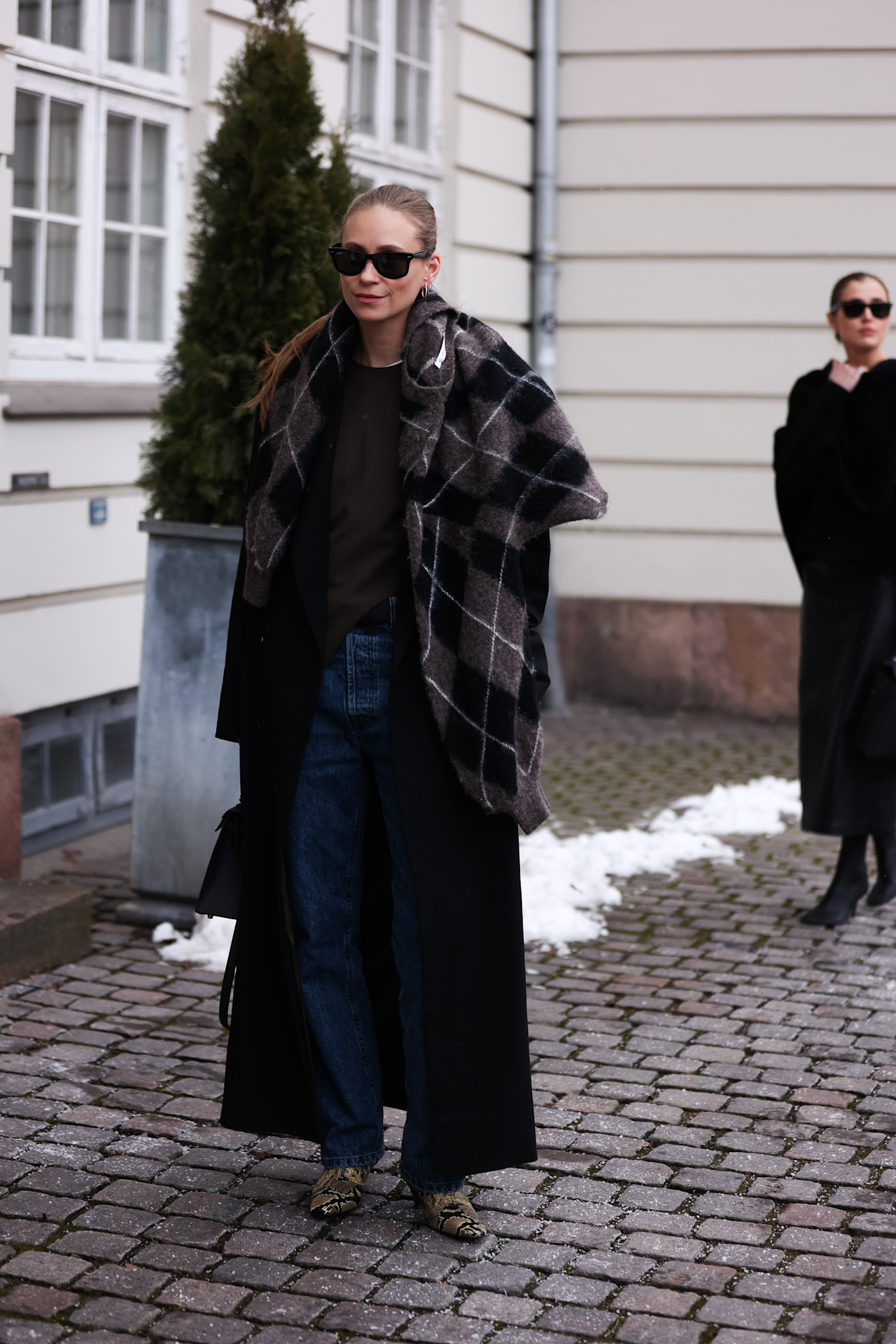fashion week attendee with argyle sweater over sweater, jeans, snakeskin boots
