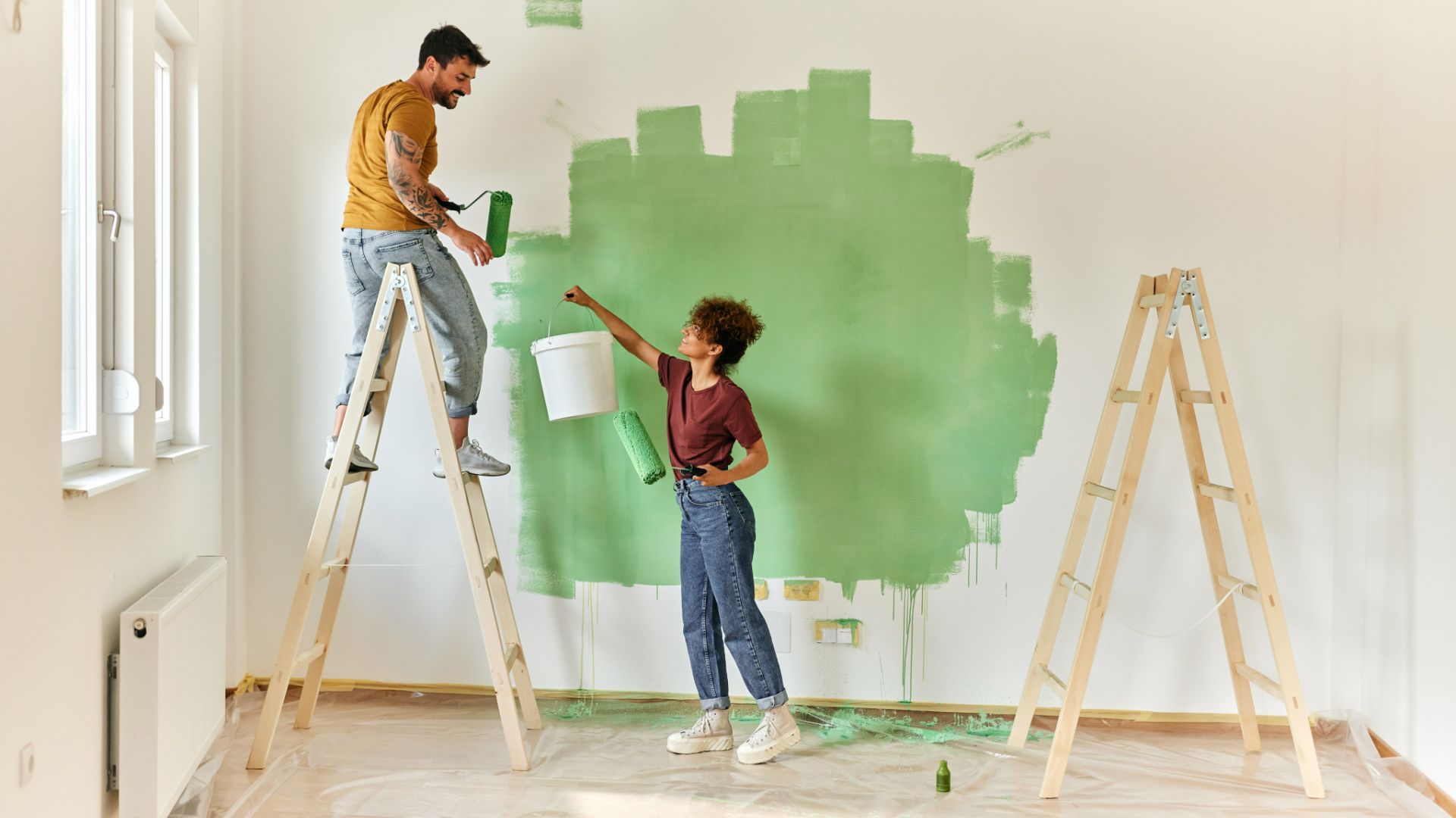 couple painting a white wall green