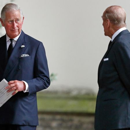 Prince Charles holding a paper and turning to look at Prince Philip