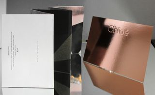 Fashion week Invitation featuring a shining bronze show with Chloe emblem and a fold-out card invitation.