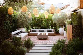 backyard with hanging lanters, festoon lights and firepit by Kate Anne Designs