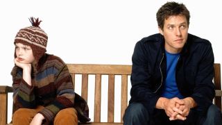 En promobild för filmen Om en pojke, där huvudrollerna Will och Marcus sitter på en bänk. Visas mot en vit bakgrund.