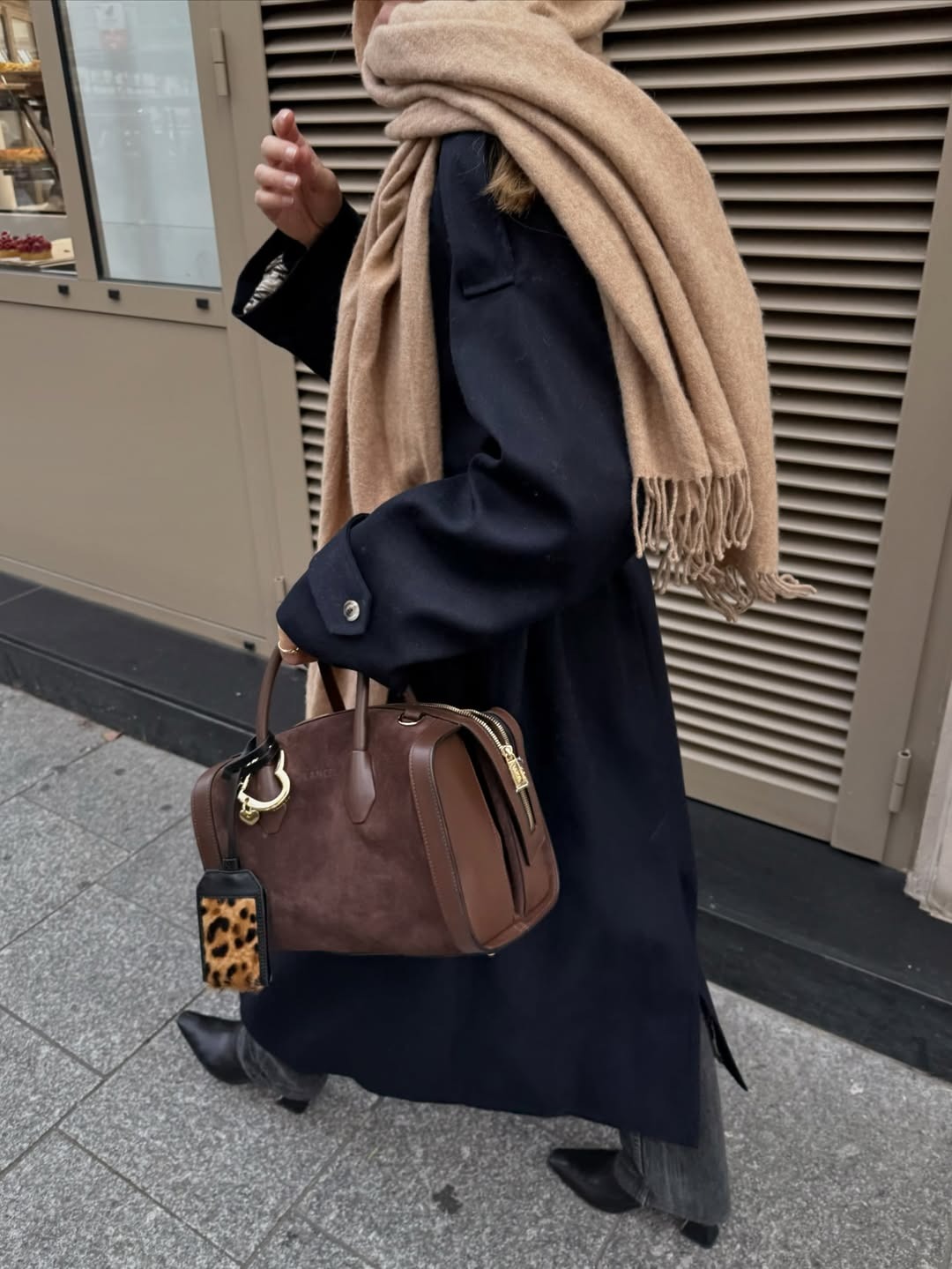 Woman in long coat and brown suede bag.