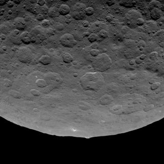 NASA's Dawn spacecraft photographed an intriguing mountain on dwarf planet Ceres protruding from a relatively smooth area. This structure rises an estimated 3 miles (5 kilometers) above the surface. Image taken on June 14, 2015.