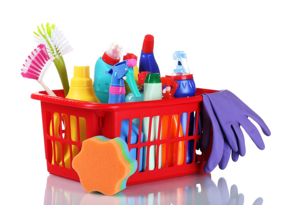 A box of household cleaning products, including spray bottles, sponges and scrubbers.