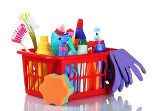 A box of household cleaning products, including spray bottles, sponges and scrubbers.